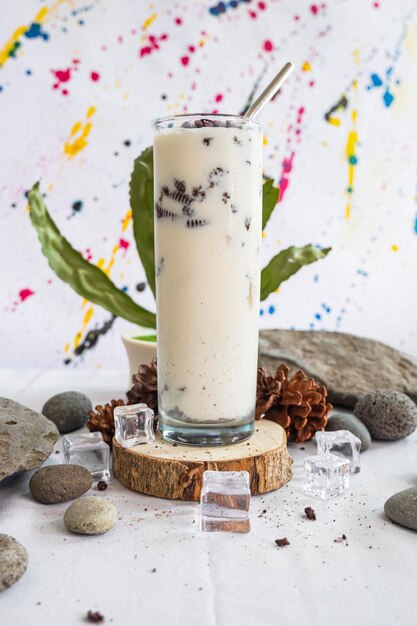 Minimalist Concept Idea.black biscuit iced milk drink on stone with green leaves on abstract background.