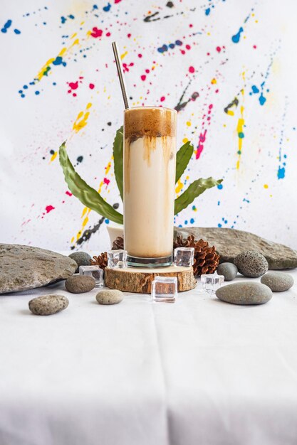 Minimalist Concept Idea.Dalgona coffee milk drink on stone with green leaves on abstract background.