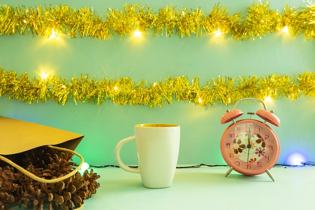製品を表示するミニマリストのコンセプトアイデア。クリスマスと新年の背景にコーヒーマグ。目覚まし時計。松の花