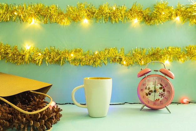 Minimalist concept idea displaying products. coffee mug on christmas and new year background. alarm clock. pine flower