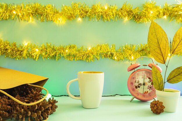 Minimalist concept idea displaying products. coffee mug on christmas and new year background. alarm clock. pine flower