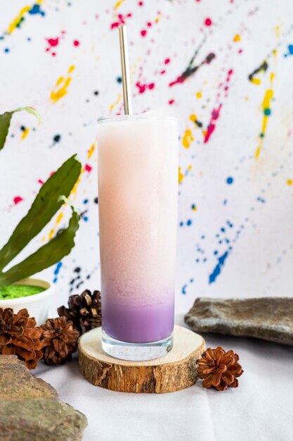 Photo minimalist concept idea. purple soda milk ice drink on stone with green leaves on abstract background.