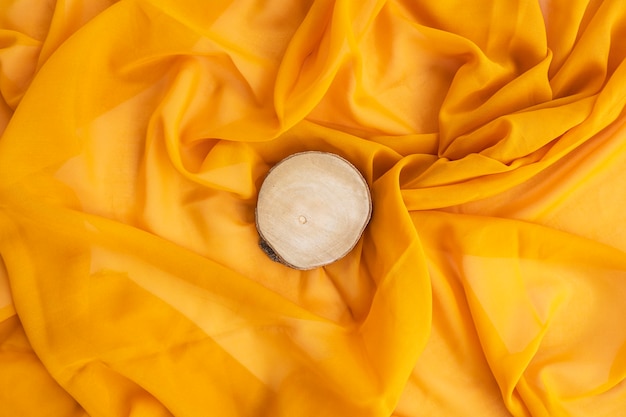 Concetto minimalista. legno rotondo su sfondo giallo sciarpa. autunno, concetto di autunno. disposizione piana, vista dall'alto, copia spazio