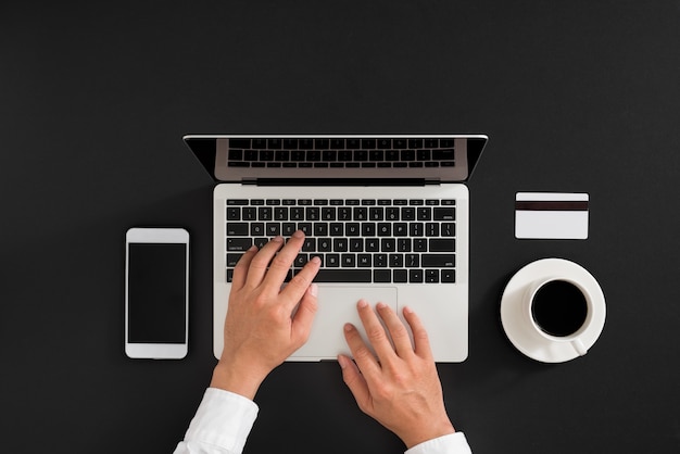 Minimalist flat lay composition of laptop, cell phone gadget, cup of coffee on table background. Workspace top view, copy space