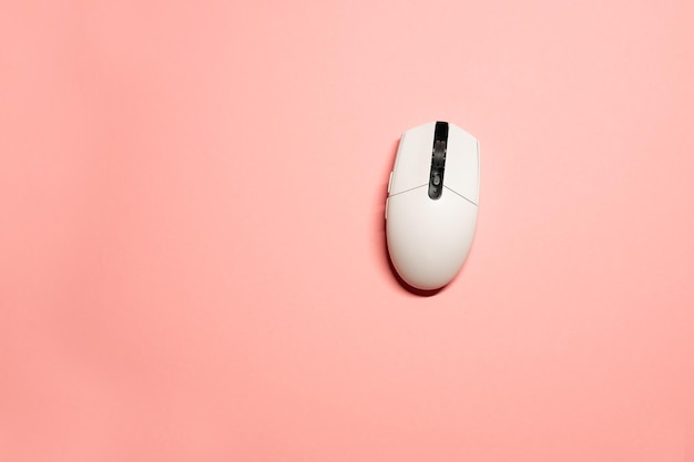 Photo minimalist flat lay photo of a wireless white plastic computer mouse on an isolated pink background