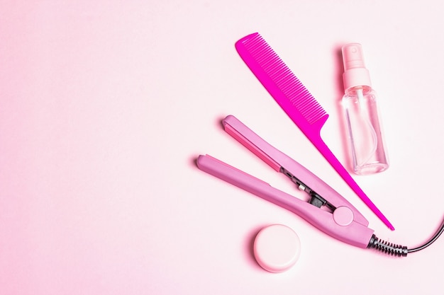 Minimalist haircare concept with hair straightener, brush, spray and oil