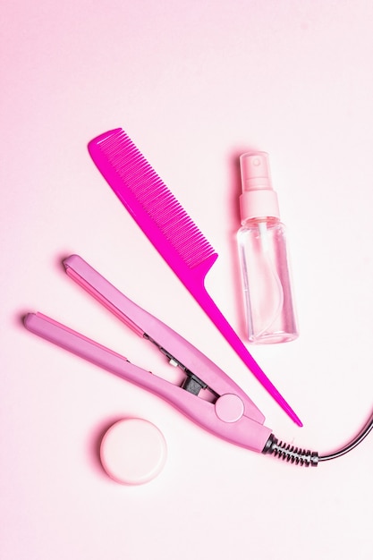 Minimalist haircare concept with hair straightener, brush, spray and oil