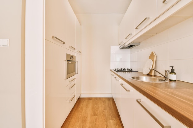 Minimalist kitchen interior with white furniture and modern appliances in a cozy house