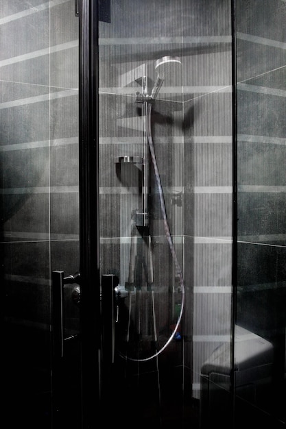 レインヘッド付きのダークグレーのタイルで完全に装飾されたミニマリストの豪華なシャワー
