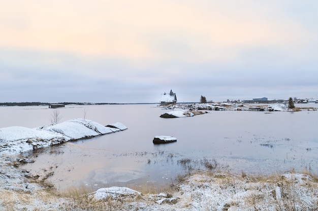 러시아 마을 Rabocheostrovsk의 해안에 정통 집이있는 미니멀리스트 눈 덮인 겨울 풍경.