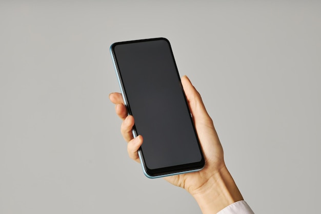 Minimalistic closeup female hand holding smartphone against white background