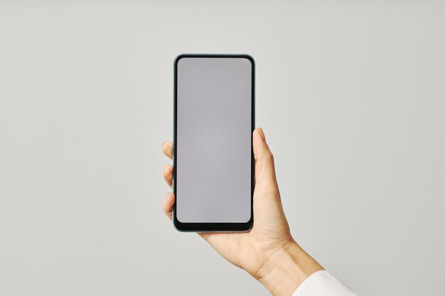 Minimalistic closeup female hand holding smartphone with blank screen mock up