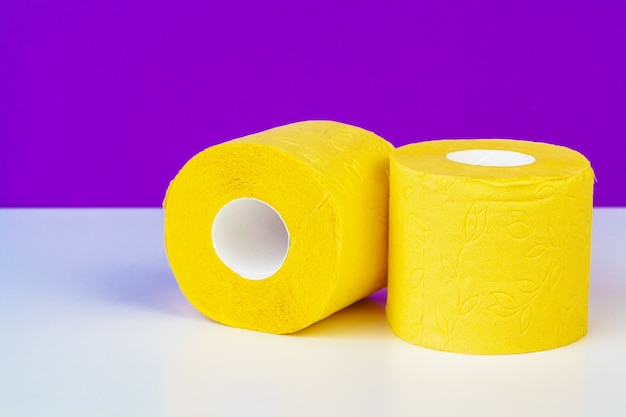 Minimalistic composition of bright yellow toilet paper rolls on purple 