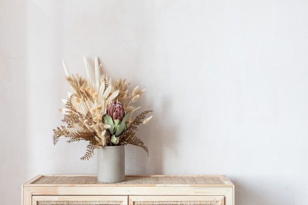 Composizione minimalista di fiori secchi in vaso cilindrico in ceramica come decorazione domestica.