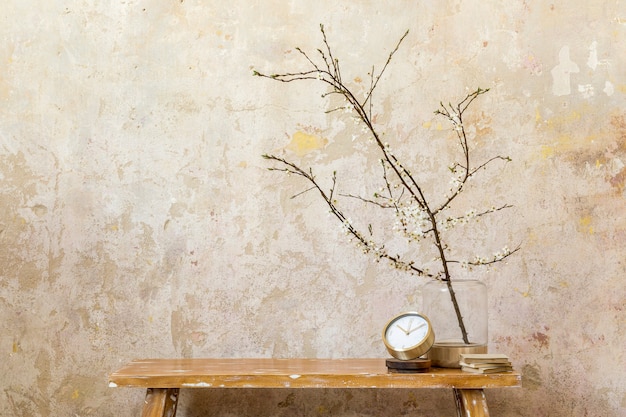 Composizione minimalista dell'interno del soggiorno con orologio d'oro, panca in legno e fiori secchi in un arredamento moderno. copia spazio.