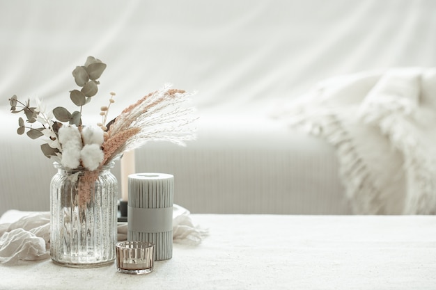 A minimalistic composition in the Scandinavian style with dried flowers in a vase and candles.