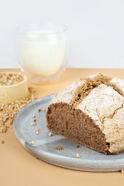 Minimalistic creative beige background with green buckwheat bread nd organic buckwheat milk. Harmless, wellness, gluten free healthy baking. Alternative bread. Copy spase