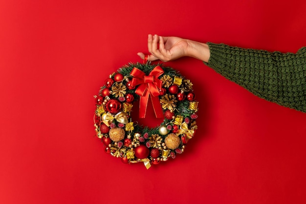 Minimalistic festive design christmas decorative wreath in female hand on red background