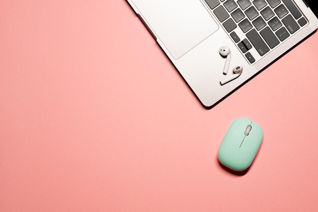 Minimalistic flat lay shot with a silver grey laptop light blue computer mouse