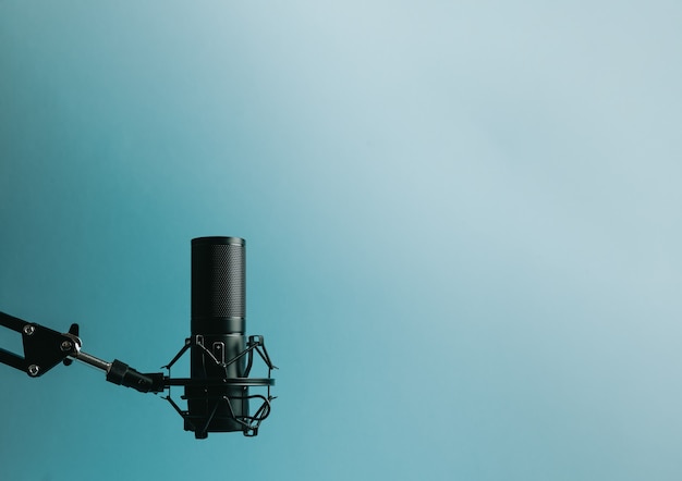 Minimalistic image of a streaming microphone over an pastel\
blue background with copy space