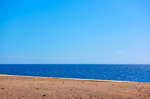 Minimalistic landscape with sea, coast and clear blue sky, may be used as background