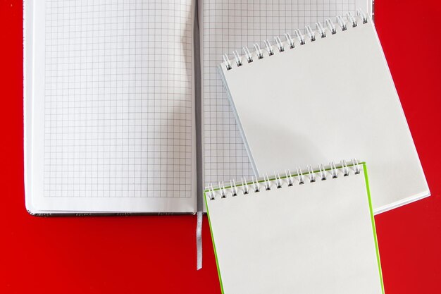 デザインのミニマルなレイアウト赤い背景にメモ用の空白のノートブックを開く