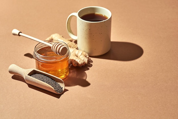 Minimalistic poster - composition with tea, lemon, honey and ginger on a brown background. Healing tea for colds.