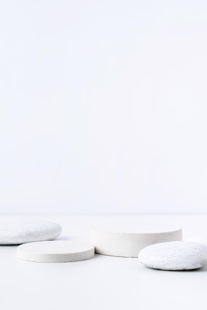 천연 화장품을 위한 흰색 배경에 돌이 있는 흰색 석고 연단의 최소한의 장면