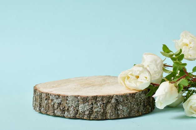 Minimalistic stage with a wooden podium on a light blue background with flowers Podium for the presentation of products and cosmetics A showcase with a stage for natural products