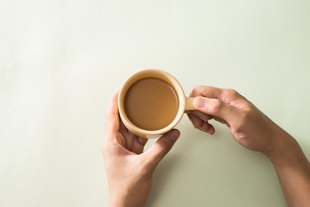 Mano di donna in stile minimalista che tiene una tazza di caffè su sfondo grigio