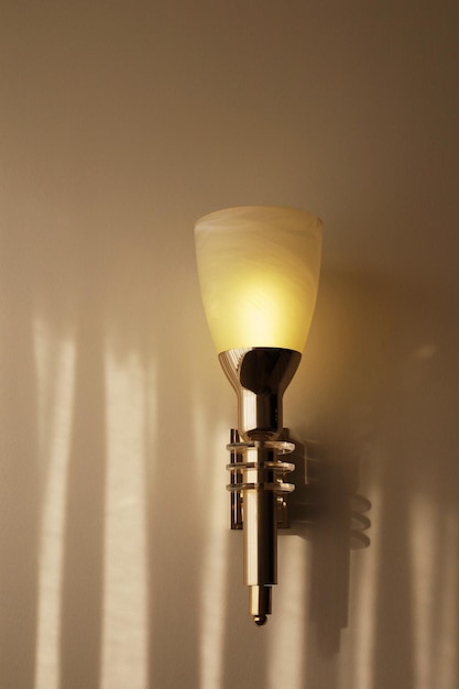 Minimalistic wall lamp in the form of a torch Dim warm light Simple luminaire on rough background with copy space Light and shadows