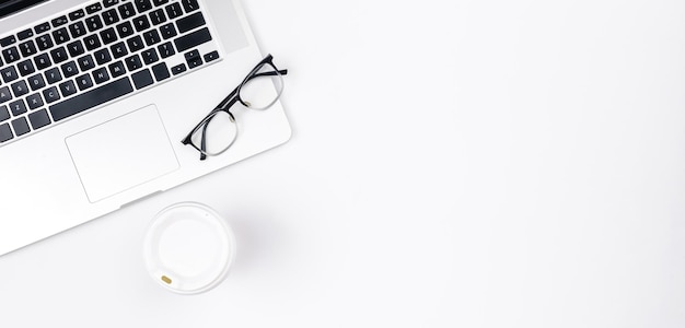 Minimalistic white background with laptop disposable paper cup and glasses