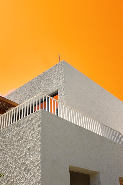 Minimalistic white building with windows on background of orange sky