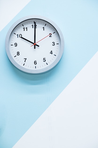 Minimalistic white wall clock with light metal on a blue white background. time concept.