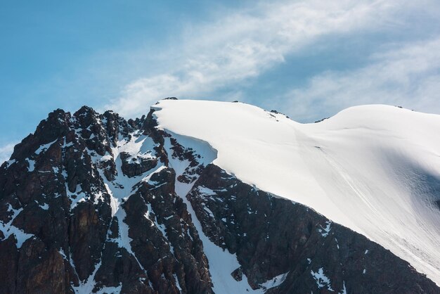 Minimalistisch alpenlandschap met besneeuwde bergtop en scherpe rotsen in zonlicht Eenvoudig minimalisme met ingesneeuwde berg in blauwe lucht Minimaal uitzicht op besneeuwde bergtop op zeer grote hoogte