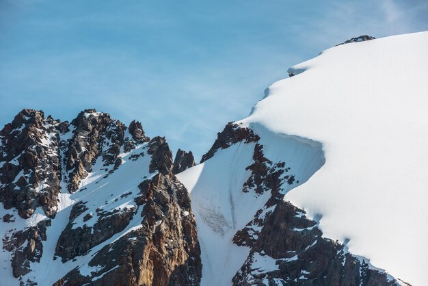 Minimalistisch alpenlandschap met besneeuwde bergtop en scherpe rotsen in zonlicht Eenvoudig minimalisme met ingesneeuwde berg in blauwe lucht Minimaal uitzicht op besneeuwde bergtop op zeer grote hoogte