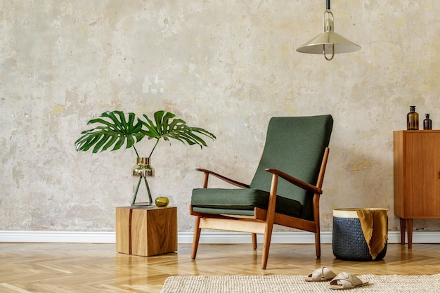 Minimalistisch concept van interieur met retro fauteuil, hanglamp, houten commode, tropisch blad in vaas, houten kubus, tapijt, mand en elegante accessoires in modern interieur.