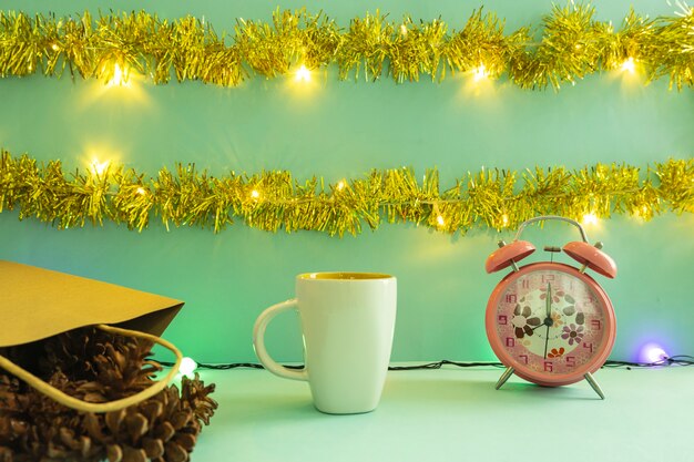 Minimalistisch conceptidee dat producten weergeeft. koffiemok op Kerstmis en Nieuwjaar achtergrond. wekker. pijnboom bloem