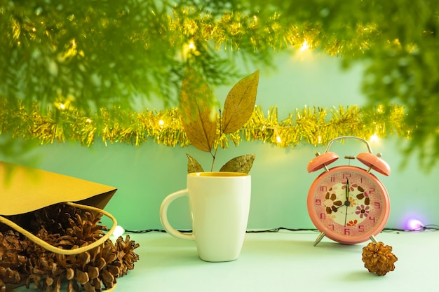 Minimalistisch conceptidee dat producten weergeeft. koffiemok op kerstmis en nieuwjaar achtergrond. wekker. pijnboom bloem