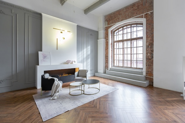 Minimalistisch interieur van een ultramodern open appartement met witte en grijze muren met een reliëf en grijs stijlvol gestoffeerd meubilair en grote ramen