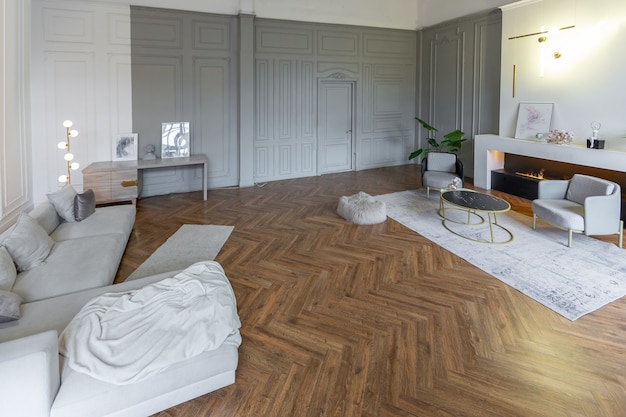 Minimalistisch interieur van een ultramodern open appartement met witte en grijze muren met een reliëf en grijs stijlvol gestoffeerd meubilair en grote ramen