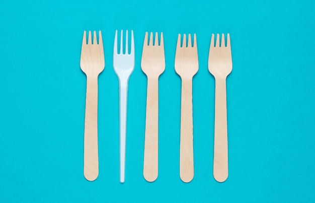 Minimalistisch milieuconcept. Houten en plastic vorken op een roze blauwe achtergrond. Creatieve eco achtergrond. Bovenaanzicht