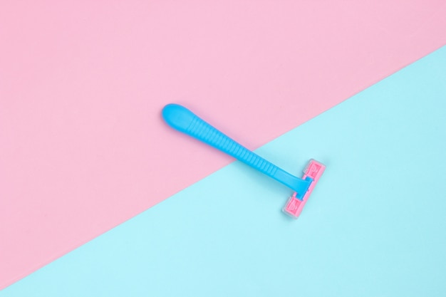 Minimalistisch schoonheidsconcept. Plue plastic scheermesje op blauw roze pastel. Bovenaanzicht