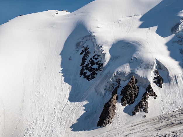 Minimalistisch sneeuwberglandschap met grote gletsjer in zonlicht Eenvoudig besneeuwd minimalisme met glaciaal in de zon Minimaal alpine uitzicht op sneeuwbergtoppen op zonnige dag