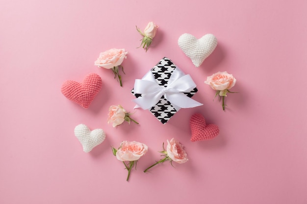 Minimalistische achtergrond voor Valentijnsdag Een bannerlay-out met een gebreid hart en een geschenk en rozen op een lichtroze achtergrond met ruimte voor tekst