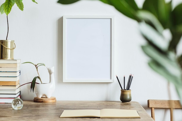 Minimalistische compositie van kantoor aan huis interieur met mock up poster frame houten bureau boeken en persoonlijke accessoires kopieer ruimte sjabloon