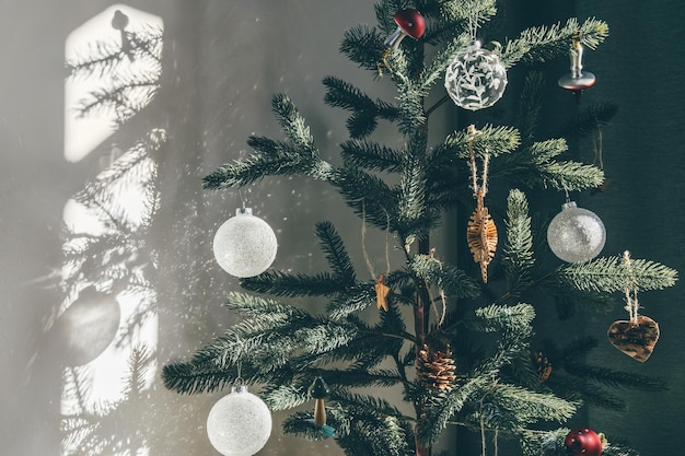 Foto minimalistische herbruikbare kerstboom met nul afval zelfgemaakt glas en houten decoraties kosmische schaduwen op de muur in zonnestralen