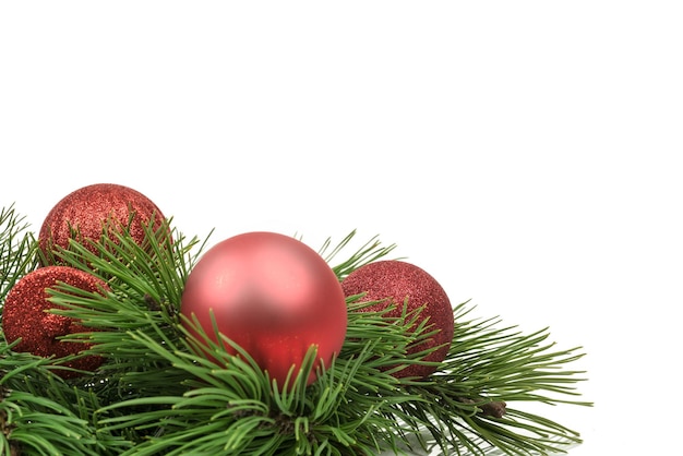 Minimalistische kerstversiering glanzende rode kerstballen en kralen op grenen twijgen geïsoleerd op een witte achtergrond met kopie ruimte place