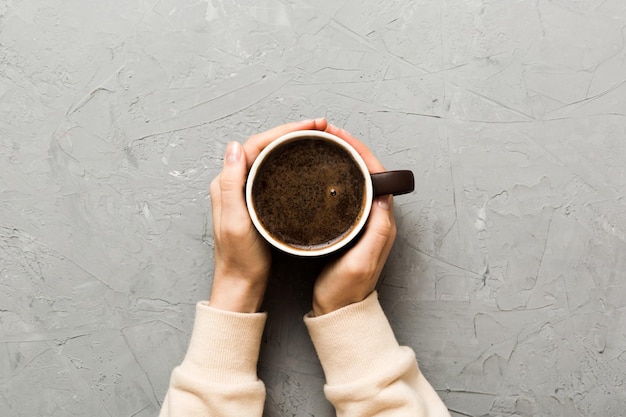 Minimalistische stijl vrouw hand met een kopje koffie op gekleurde achtergrond Plat lag bovenaanzicht cappuccinokop Lege plaats voor tekstkopieerruimte Koffieverslaving Bovenaanzicht plat leggen