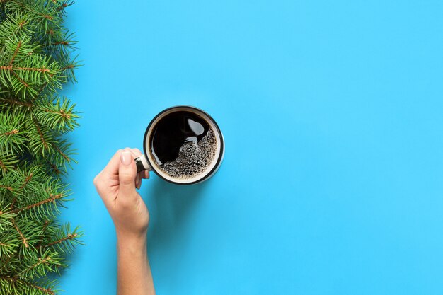 Minimalistische stijl vrouw hand met een mok koffie op blauw